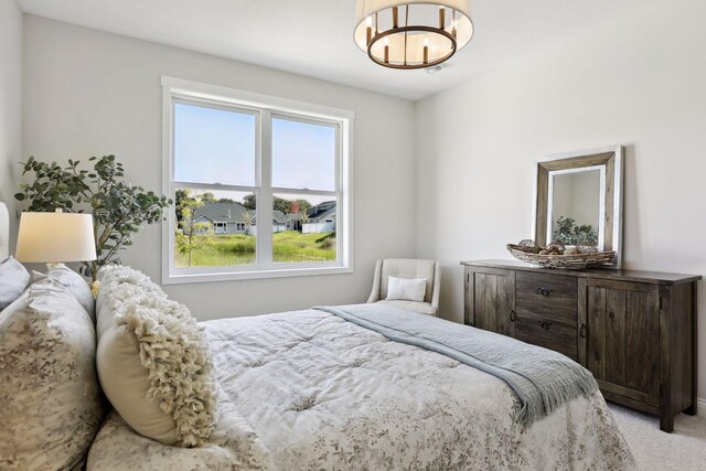 bedroom with light carpet and a chandelier