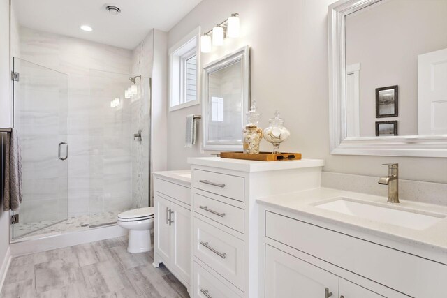 full bath featuring visible vents, toilet, a shower stall, vanity, and wood finished floors