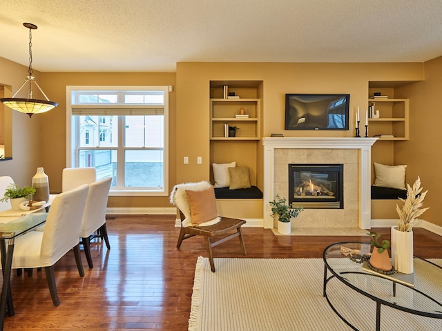 interior space with built in shelves, a fireplace, dark hardwood / wood-style flooring, and a textured ceiling