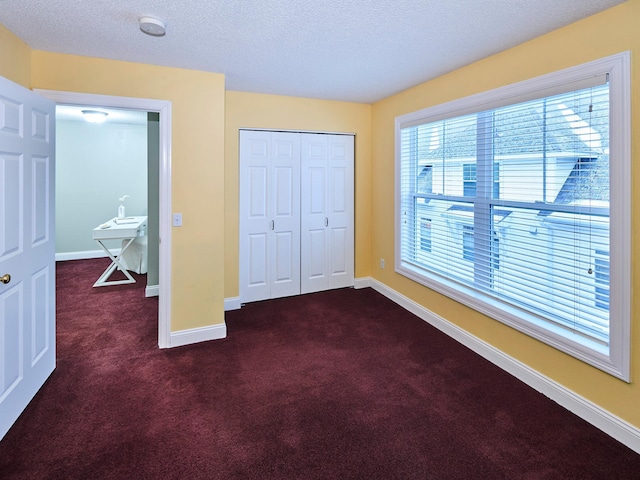 unfurnished bedroom featuring a closet, a textured ceiling, and dark colored carpet