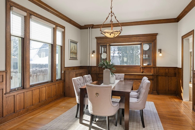 dining space featuring a wainscoted wall, plenty of natural light, and crown molding