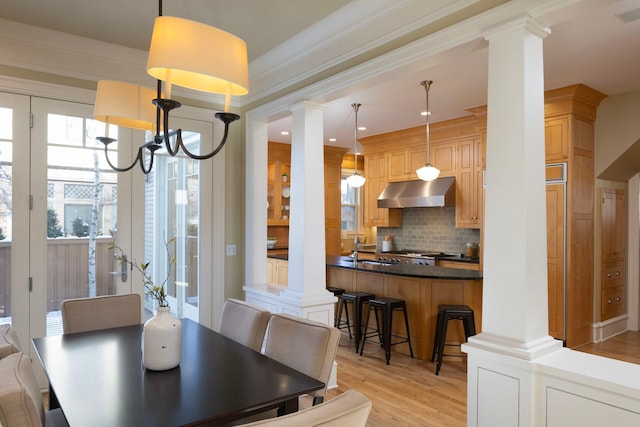 dining space with light wood-style floors and decorative columns