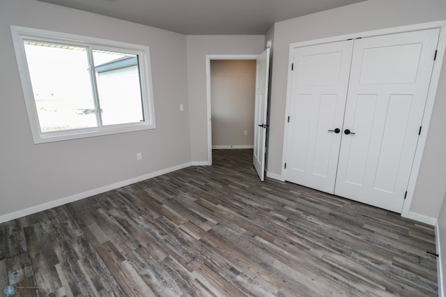 unfurnished bedroom featuring dark wood-type flooring and a closet