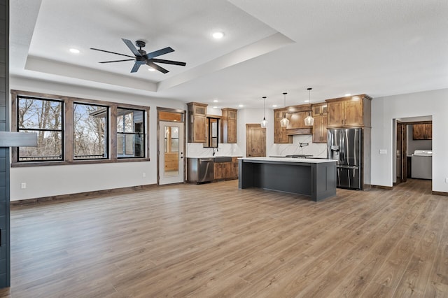 kitchen featuring stainless steel appliances, a raised ceiling, a kitchen island, and pendant lighting