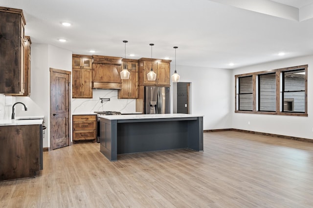 kitchen with sink, custom exhaust hood, a center island, hanging light fixtures, and appliances with stainless steel finishes