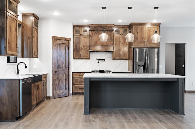 kitchen featuring sink, a center island, light hardwood / wood-style flooring, pendant lighting, and stainless steel appliances