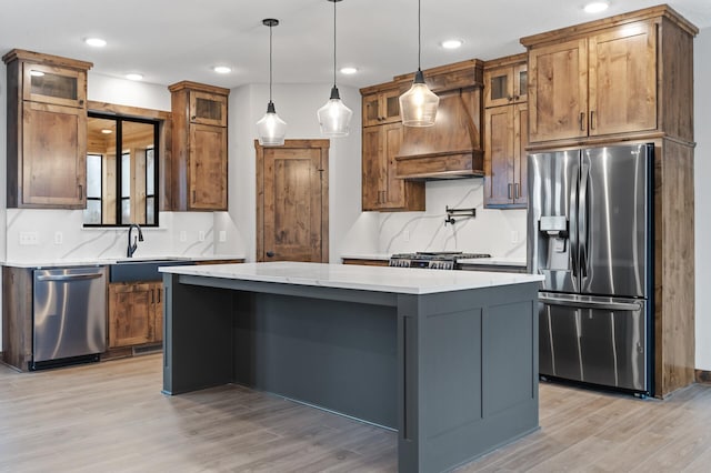 kitchen featuring premium range hood, a center island, pendant lighting, stainless steel appliances, and light stone countertops