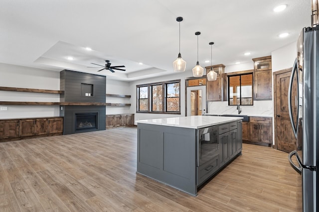 kitchen with a spacious island, decorative light fixtures, stainless steel fridge, a raised ceiling, and a fireplace