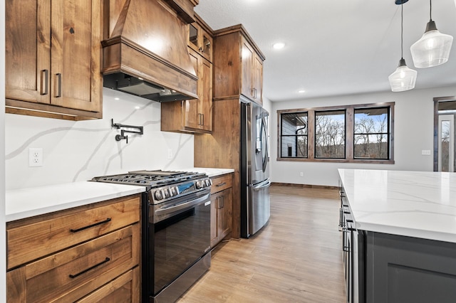 kitchen with premium range hood, stainless steel appliances, light stone counters, light hardwood / wood-style floors, and decorative light fixtures