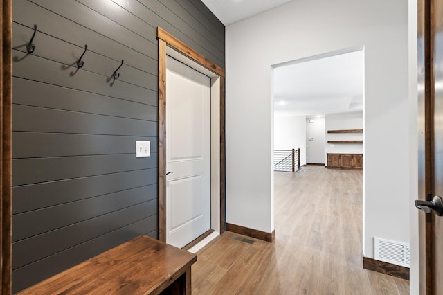 mudroom with wood walls and light wood-type flooring