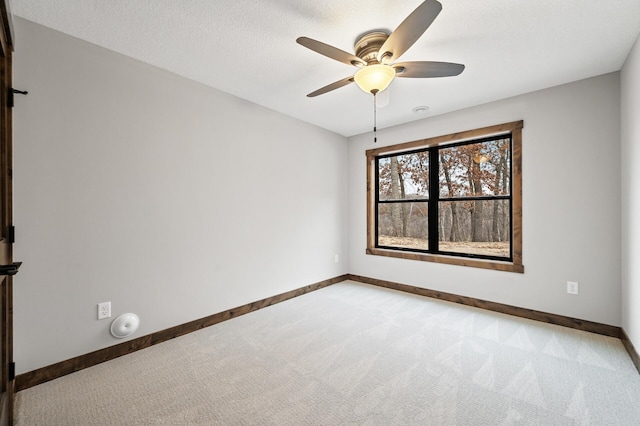 carpeted spare room featuring ceiling fan and a textured ceiling