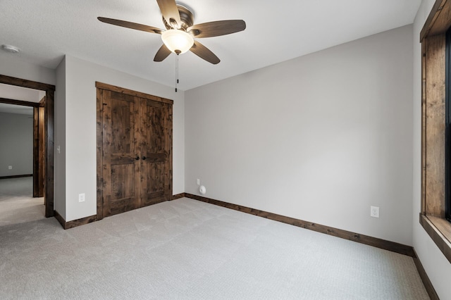 unfurnished bedroom with ceiling fan and light colored carpet