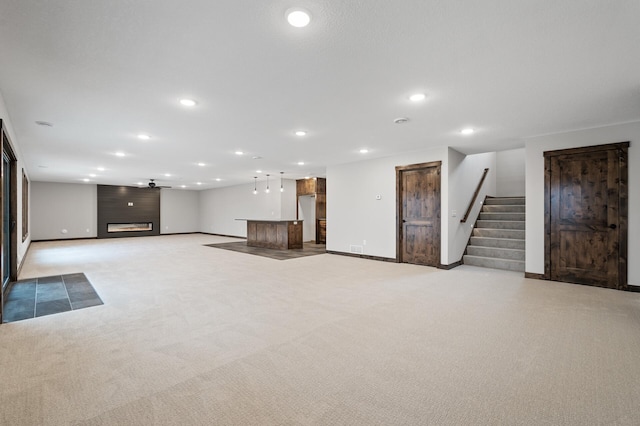 basement with light colored carpet, a large fireplace, ceiling fan, and bar area