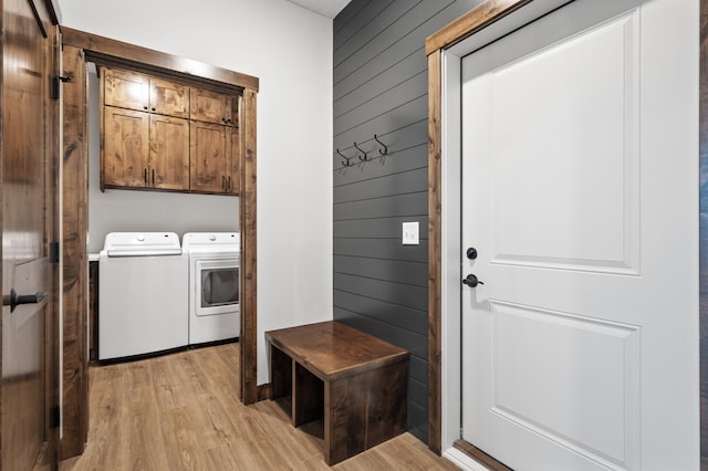 laundry room featuring cabinets, independent washer and dryer, light hardwood / wood-style flooring, and wood walls