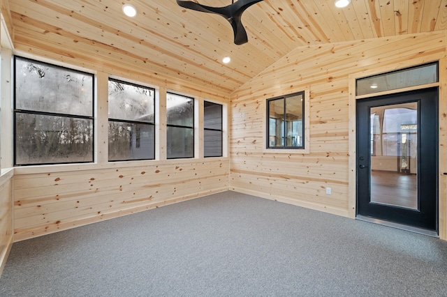 empty room featuring wood walls, wood ceiling, vaulted ceiling, carpet floors, and ceiling fan