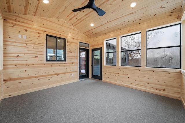 carpeted empty room featuring vaulted ceiling, ceiling fan, wooden ceiling, and wooden walls