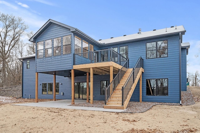 back of property with a wooden deck, a sunroom, and a patio