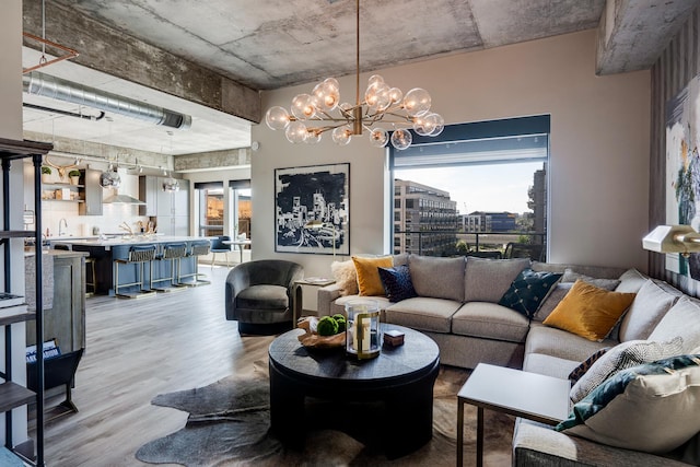 living room with a healthy amount of sunlight, a chandelier, sink, and light wood-type flooring