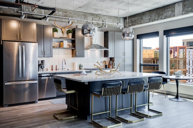 kitchen featuring a kitchen bar, sink, a center island with sink, appliances with stainless steel finishes, and light hardwood / wood-style floors