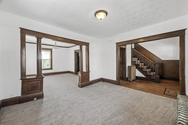 818 Sherburne Ave, Saint Paul, MN 55104 - unfurnished living room featuring carpet, a chandelier, ornate columns, and baseboards