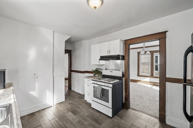 818 Sherburne Ave, Saint Paul, MN 55104 - kitchen with gas range gas stove, under cabinet range hood, white cabinets, dark wood-style flooring, and freestanding refrigerator