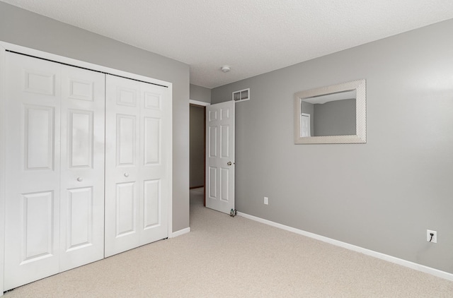 unfurnished bedroom with light colored carpet, a closet, and a textured ceiling