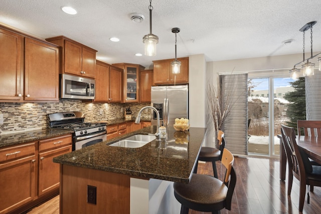 kitchen with a sink, stainless steel appliances, brown cabinets, and backsplash