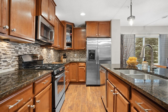 kitchen with light wood-style flooring, brown cabinetry, appliances with stainless steel finishes, and a sink