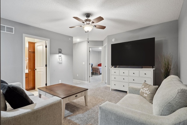 living area featuring a ceiling fan, baseboards, visible vents, a textured ceiling, and light carpet