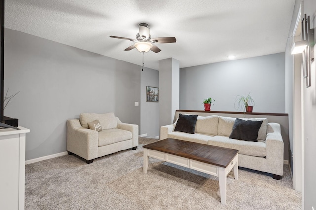 living room with ceiling fan, a textured ceiling, baseboards, and carpet