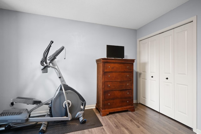 exercise room featuring baseboards and wood finished floors