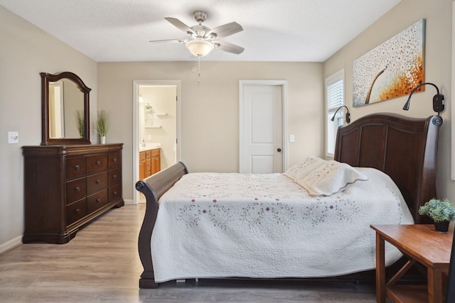 bedroom with light wood-style flooring, ensuite bath, baseboards, and a ceiling fan