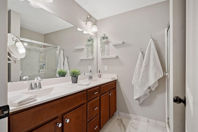 full bathroom with a sink, marble finish floor, a stall shower, and double vanity