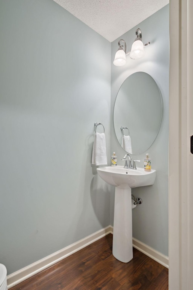 bathroom featuring wood finished floors, baseboards, and a textured ceiling