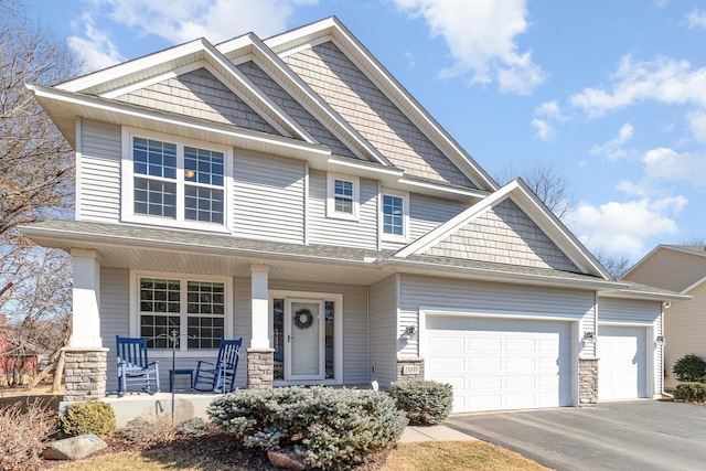 craftsman-style home with aphalt driveway, covered porch, and an attached garage