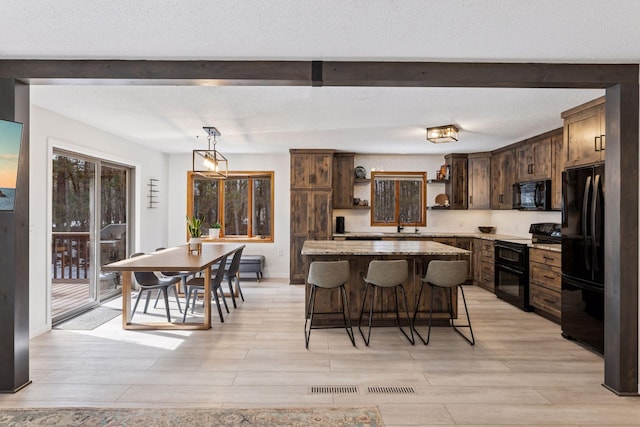 kitchen with black appliances, a kitchen breakfast bar, dark brown cabinets, and open shelves