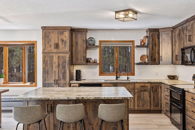 kitchen with open shelves, a kitchen breakfast bar, black appliances, and a sink