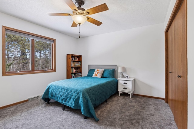 carpeted bedroom with visible vents, baseboards, a textured ceiling, and a closet