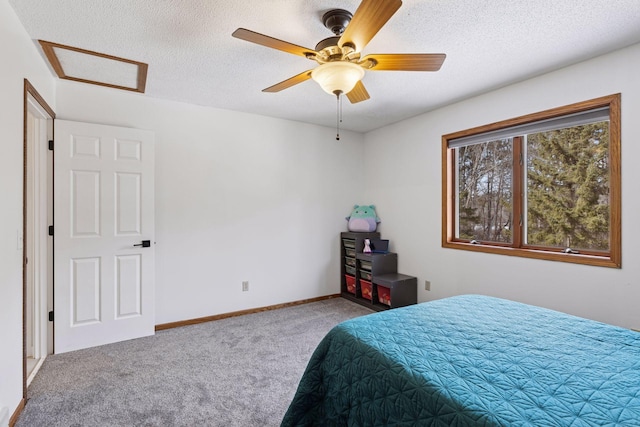 carpeted bedroom featuring baseboards, a textured ceiling, attic access, and a ceiling fan