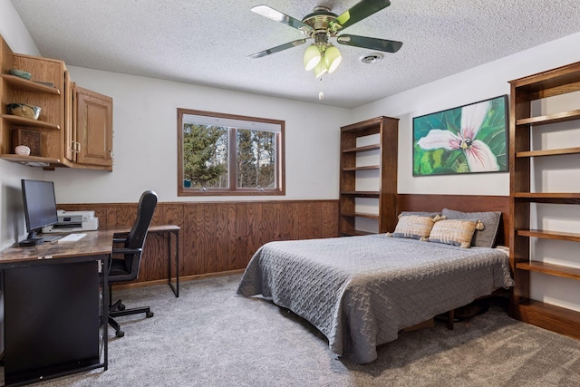 carpeted bedroom featuring a textured ceiling, wood walls, and wainscoting