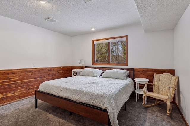 bedroom with wainscoting, wood walls, and carpet