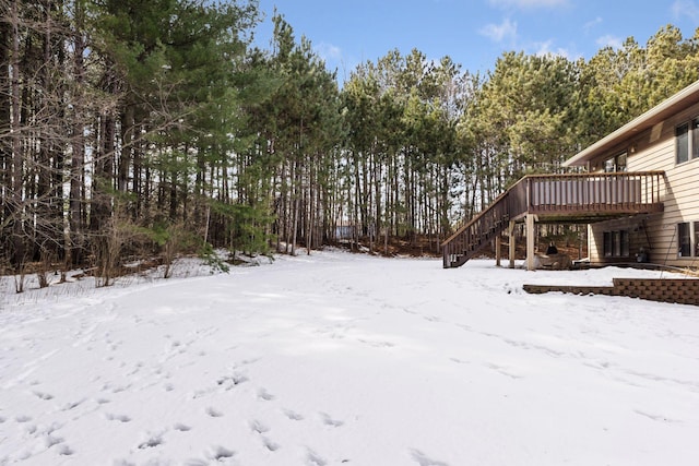 snowy yard with stairs and a wooden deck