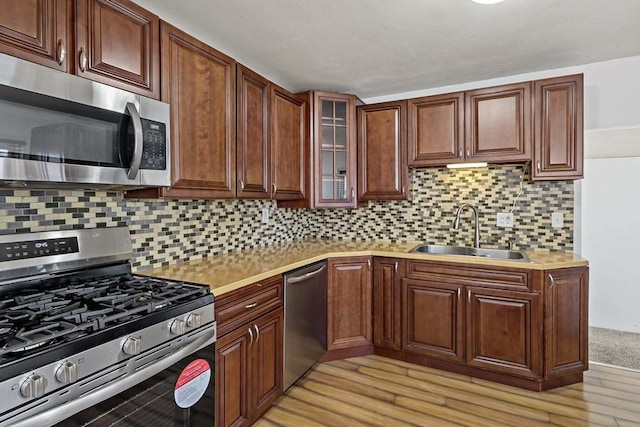 kitchen featuring tasteful backsplash, sink, light wood-type flooring, and appliances with stainless steel finishes