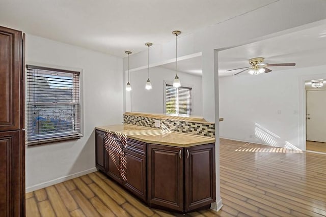 kitchen featuring backsplash, decorative light fixtures, light hardwood / wood-style flooring, and ceiling fan