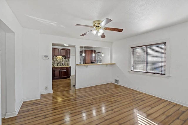 unfurnished living room featuring ceiling fan and dark hardwood / wood-style flooring