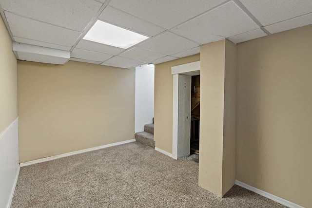 basement featuring a paneled ceiling and carpet flooring