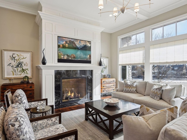 living room with a fireplace, a notable chandelier, wood-type flooring, and ornamental molding