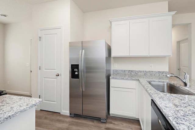 kitchen featuring stainless steel appliances, light stone countertops, sink, and white cabinets