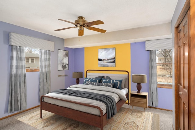 bedroom with ceiling fan, baseboards, and light colored carpet