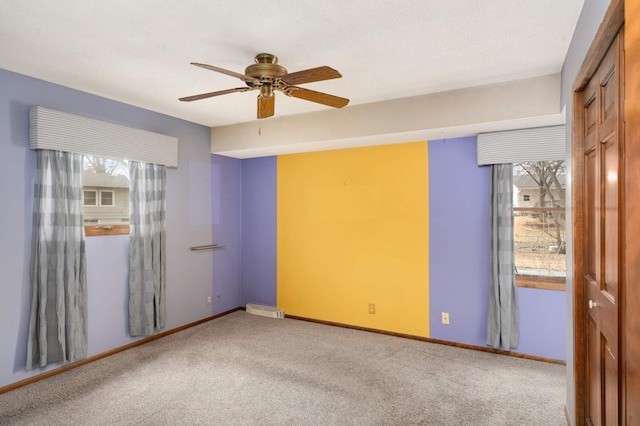 carpeted spare room featuring ceiling fan and baseboards